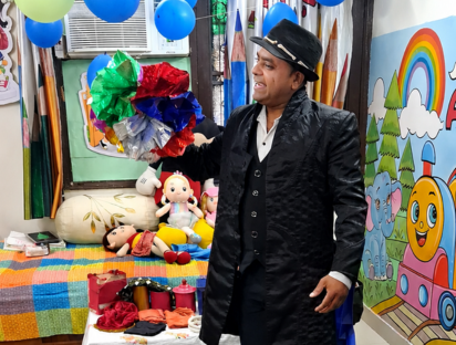 A magician performer entertaining children with colourful pom-poms and toys