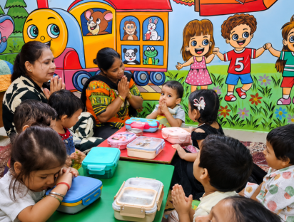 Children and teachers praying together before lunch in a bright classroom